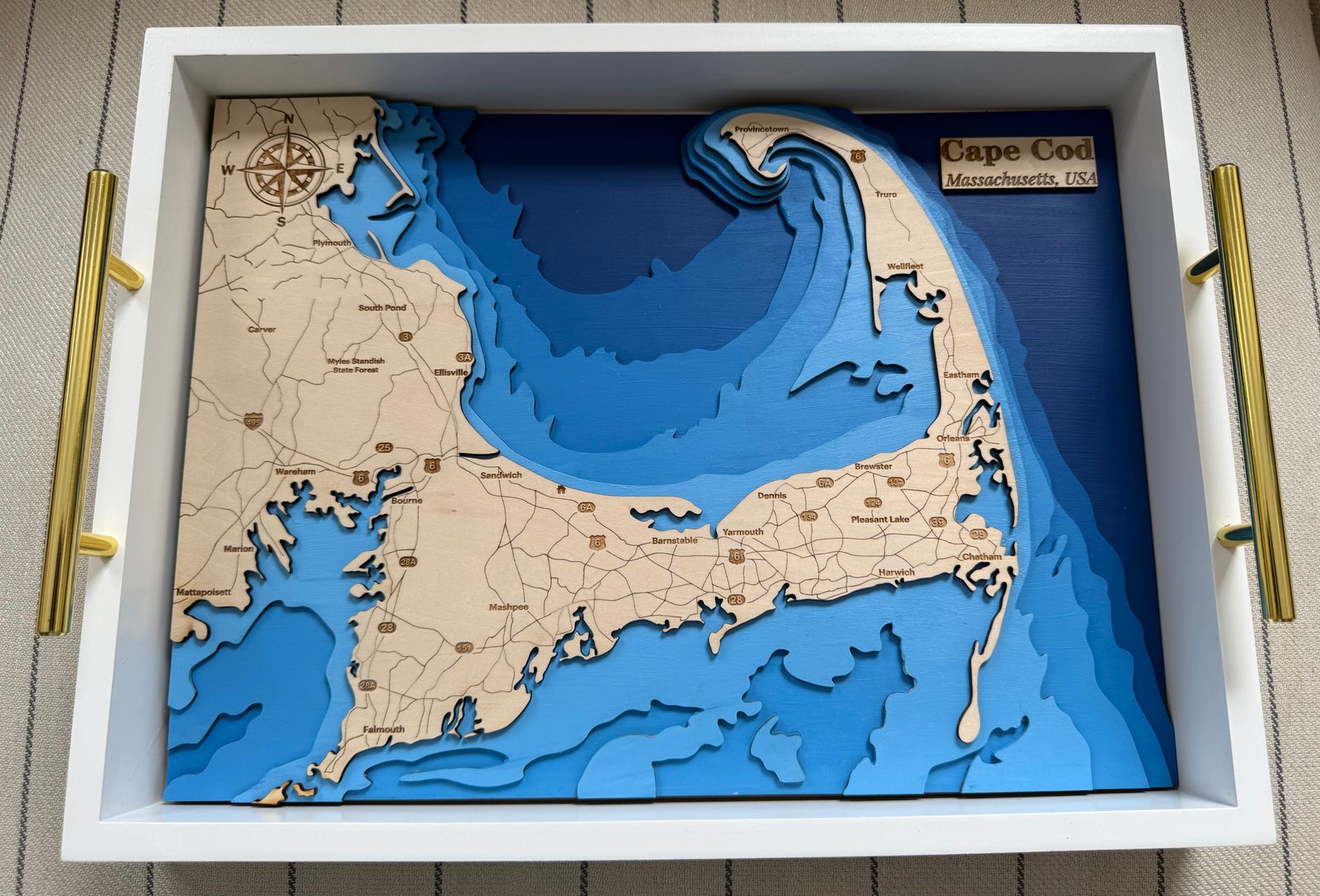 Cape Cod wooden map with blue depth layers in a white serving tray